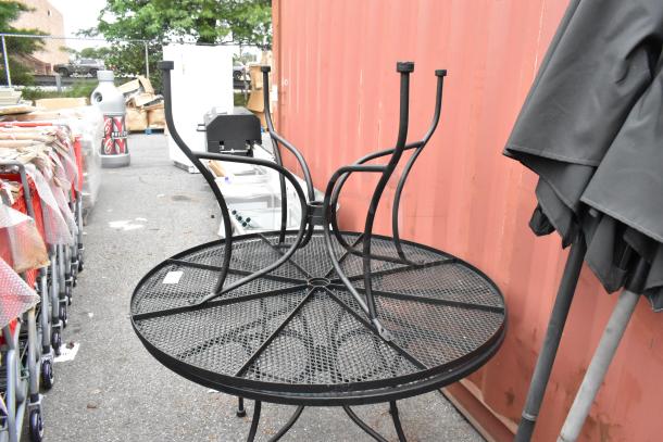 2 black metal mesh round patio tables with 2 matching black patio umbrellas, in good condition, ideal for outdoor use.