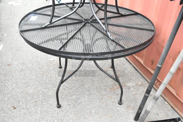 2 black metal mesh round patio tables with sturdy legs, featuring 2 black patio umbrellas. Durable outdoor furniture set.