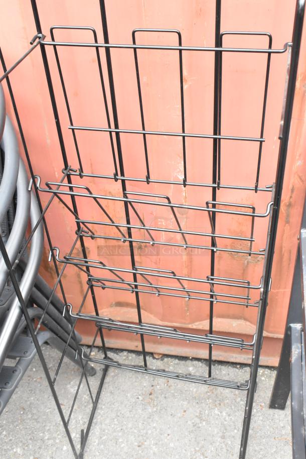 Black metal newspaper rack with four shelves, suitable for display; in good condition.