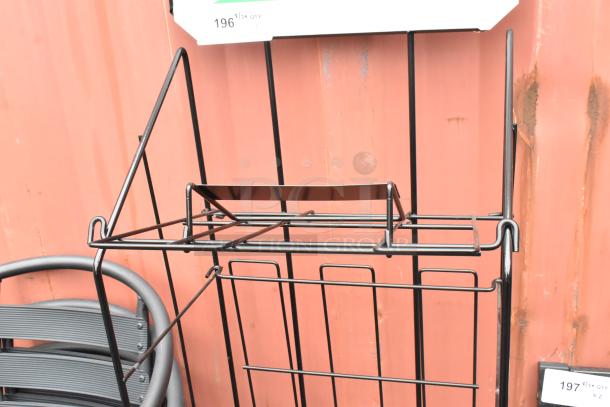Black newspaper rack with wireframe design, sturdy metal construction, minimal wear, ideal for display or storage.