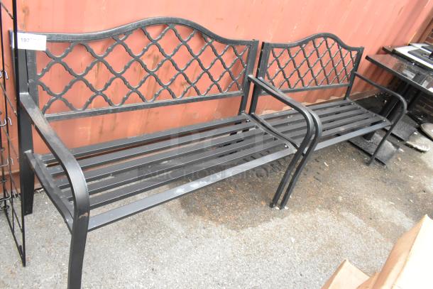 2 black metal benches with decorative backrests and armrests in good condition. Auction lot tag visible.