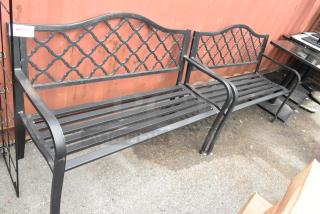 2 black metal benches with decorative backrests and armrests in good condition. Auction lot tag visible.