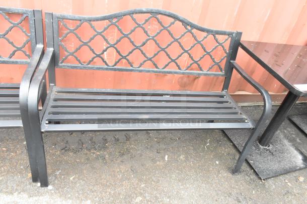 2 black metal benches with armrests, lattice back design, in used condition.