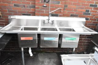 Regency 600S31416212 stainless steel 3 bay sink with dual drain boards, faucet, and handles; labels indicate wash, rinse, sanitize.