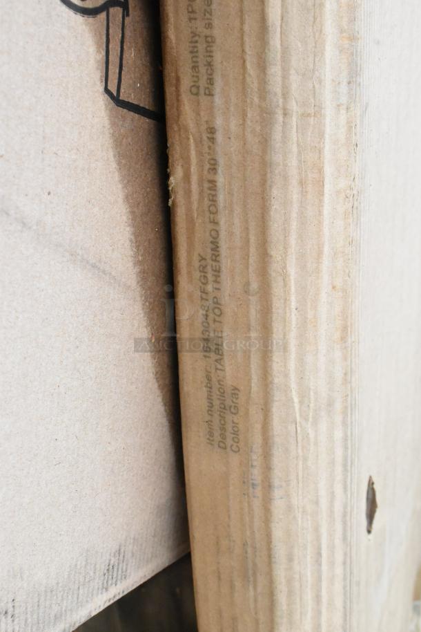Cardboard packaging with "1643048TFGRY" label for a gray Lancaster Table & Seating 30x48" MDF table top.