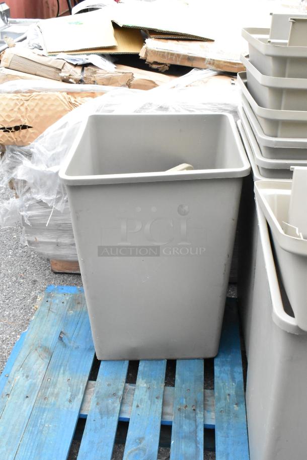 Tan poly trash can, slightly scratch and dented, includes four lids, stacked on a blue pallet.