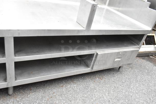 Stainless steel commercial equipment stand with under shelves, two drawers, and sturdy legs, in good condition. Ideal for kitchen use.