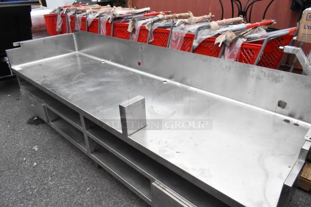 Stainless steel commercial equipment stand with under shelves and two drawers, showing some wear, suitable for heavy-duty use.