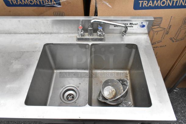 Stainless steel table with single bay and two bay sinks, showing faucet and drain, slightly worn condition.