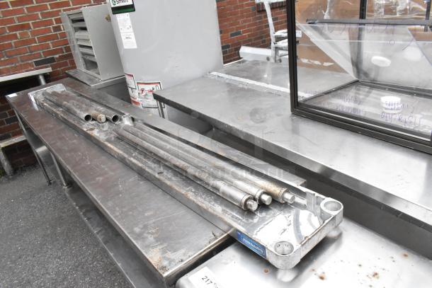 Metal shelf components, including rods and brackets, displayed on a stainless steel surface. Slightly worn condition.
