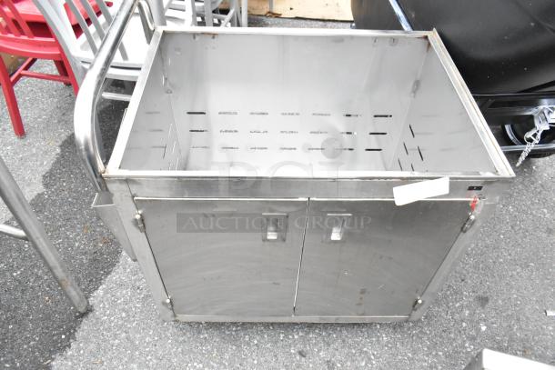 Stainless steel cart with commercial casters, open top, dual front doors, built-in handles, minor wear visible.