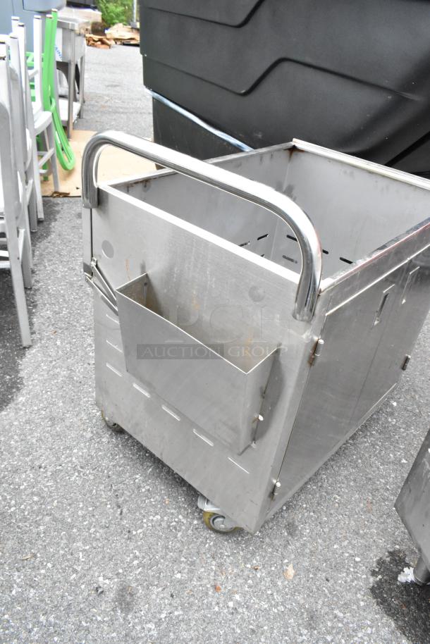 Stainless steel cart on commercial casters, featuring a side container and sturdy handle. Used condition with visible wear.