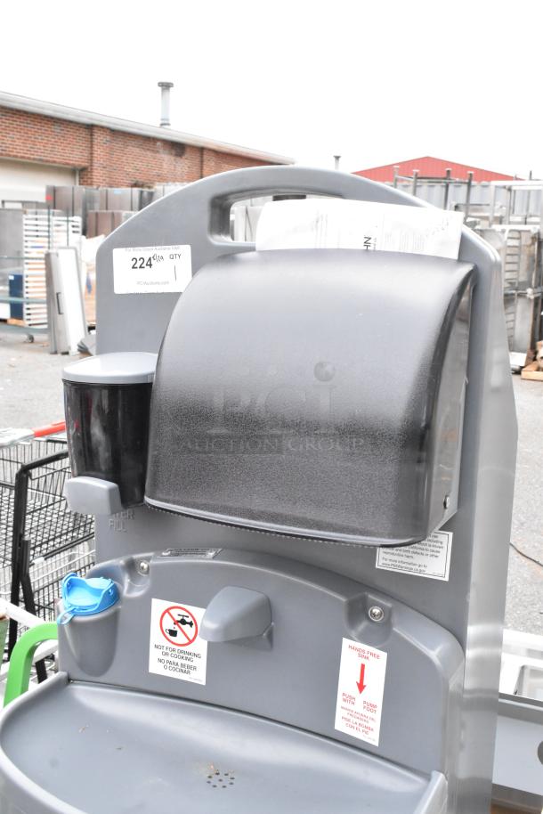 Polyjohn gray portable hand washing sink with attached dispenser, foot pedal operation, and caution labels. Slightly used condition.