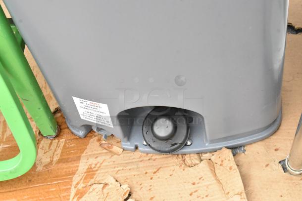Polyjohn gray poly portable hand washing sink with a drainage plug shown. Label indicates unit must be drained before transport.