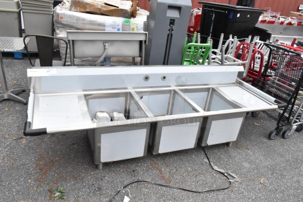 BRAND NEW Regency 600S31824218 stainless steel 3-bay sink with dual drain boards, scratches and dents visible, labels attached.