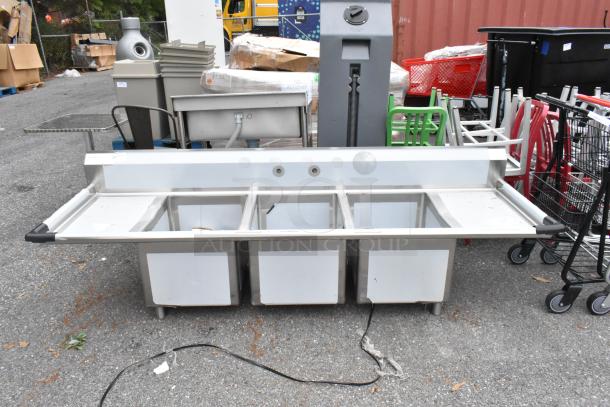 BRAND NEW Regency 600S31824218 stainless steel 3 bay sink with dual drain boards, minor scratches and dents visible.