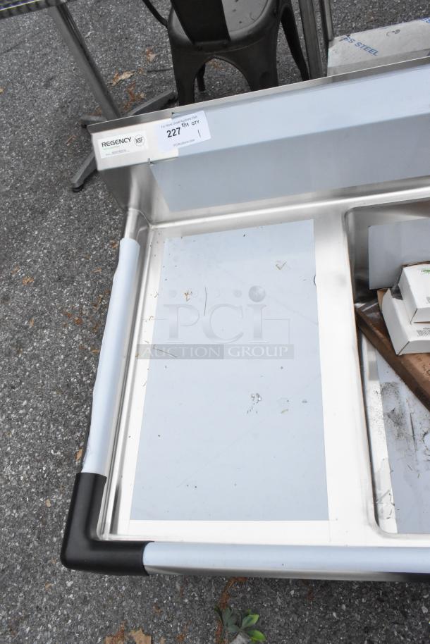 BRAND NEW Regency 600S31824218 stainless steel 3 bay sink with dual drain boards. Scratch and dent condition, seen with labels.