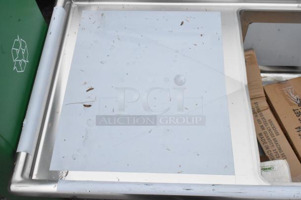 Brand new Regency 600S31824224 stainless steel 3-bay sink with dual drain boards, minor scratches visible.