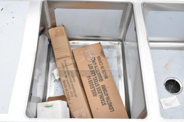 BRAND NEW Regency 600S31824224 stainless steel 3 bay sink with dual drain boards, some scratches and dents visible.