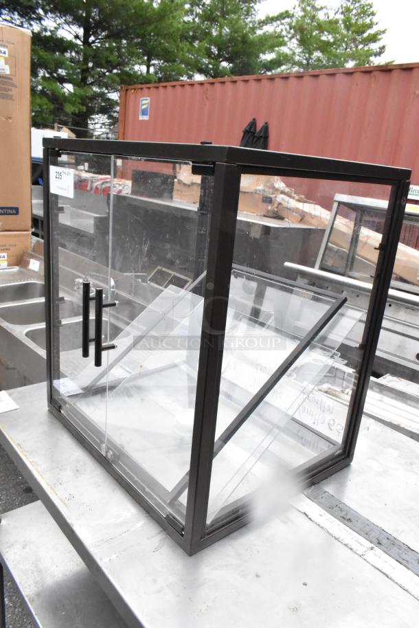 Metal countertop dry display case merchandiser, clear glass with black frame, front handles, used condition.