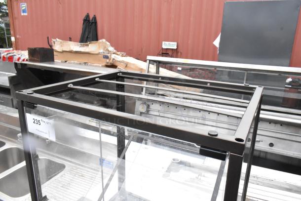 Metal countertop dry display case merchandiser with black frame, clear panels, and tag labeled "235." Good condition.