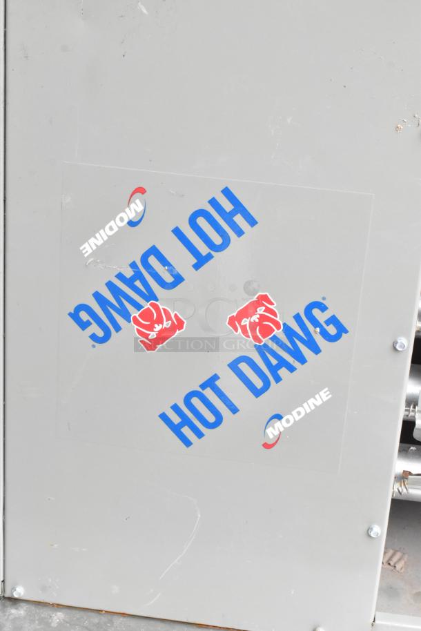 Modine HD 100AS0111FBAN commercial heater, 115 volts, 1 phase. Gray metal casing with "Hot Dawg" and Modine logo tag.