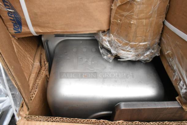 Cardboard box with visible "Vollrath" label, contains stainless steel item, likely part of scratch and dent auction lot.