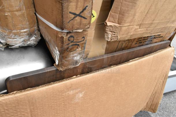 Stack of cardboard boxes containing 18 scratch and dent items for auction. Boxes show signs of wear.