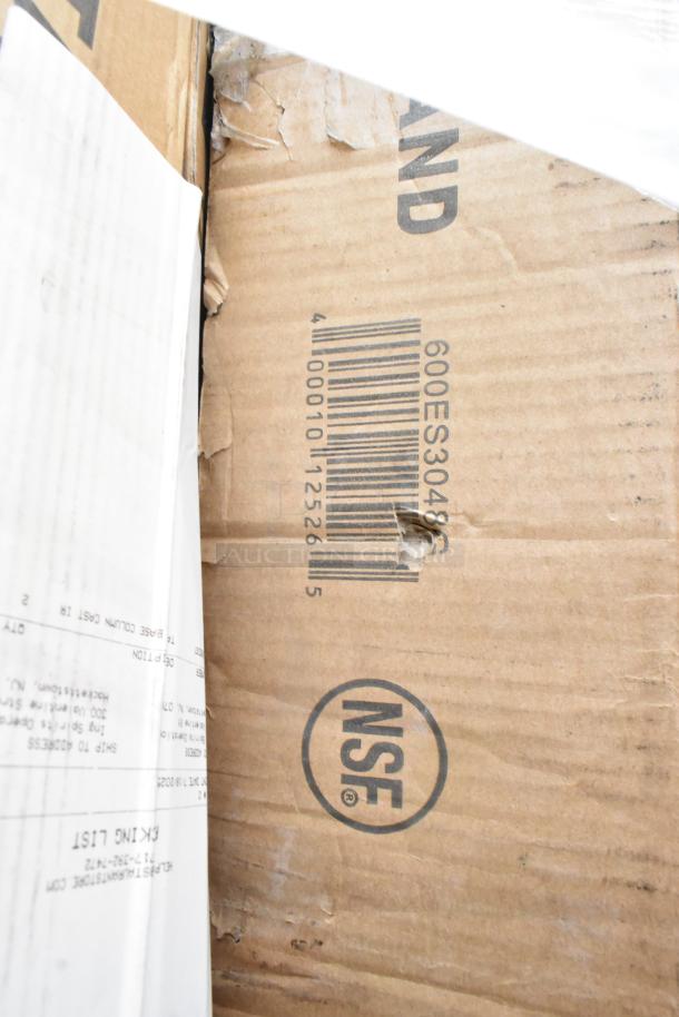 Cardboard box with visible barcode, "600ES3048G," and NSF logo, indicating a commercial-grade item, possibly a work table.