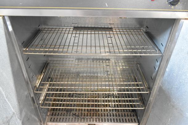Sodir stainless steel 2-door reach-in warming cabinet, 115 volts, 1 phase. Features multiple wire racks, visible wear inside.