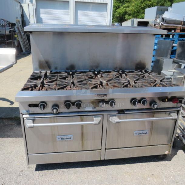 Garland 10-burner natural gas range with 2 racks, stainless steel overshelf, and casters. Used condition.