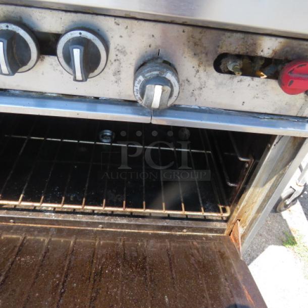 Garland 10 burner natural gas range, includes two racks and stainless steel overshelf, on casters. Used condition.