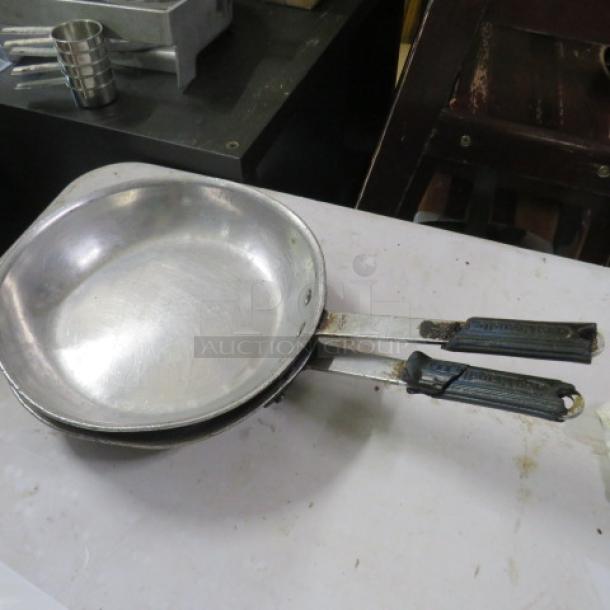 10.5-inch saute pan, metal, used condition, with black handles, stacked. Visible wear; ideal for culinary use.