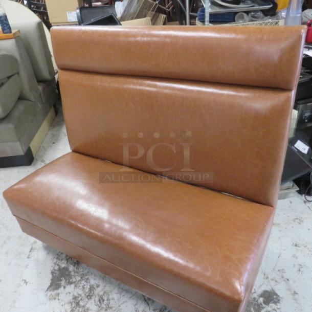 Brown cushioned booth, single-sided, 48x25x45 inches. Features faux leather upholstery. Good condition, ideal for dining spaces.