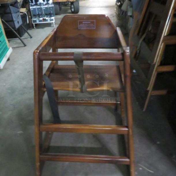 Wooden high chair with safety straps, featuring a sturdy frame and natural wood finish. Suitable for secure seating.