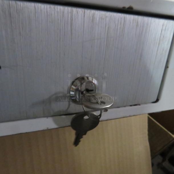 Clover cash drawer with key inserted, silver finish, visible keyhole and keyring.