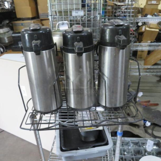 Black metal holder with three stainless steel airpots; used condition, suitable for beverage dispensing.