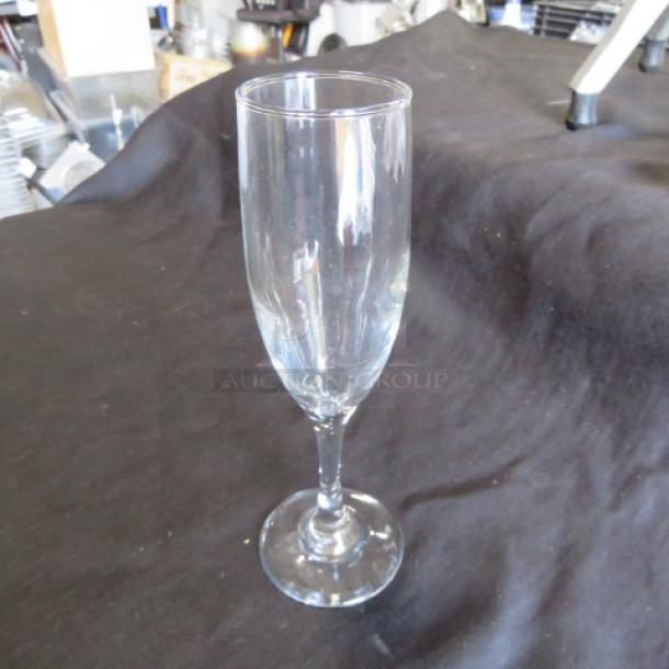 Clear glass champagne flute, tall and slender, in excellent condition. Simple design, no visible markings or labels.