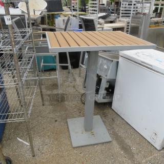 BFM synthetic teak bar height patio table, aluminum frame, 32x24x43 inches. Good condition, modern outdoor design.