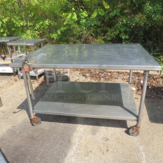 Stainless steel table with under shelf, 60x45x36 inches, includes 10lb can opener. Mounted on casters, outdoor setting.