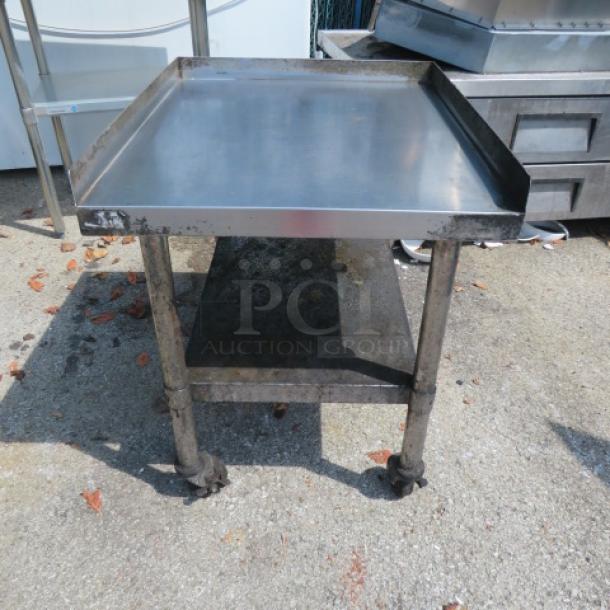 Stainless steel equipment table, 25x30x30 inches, with undershelf and casters, used condition, ideal for kitchen or workshop.