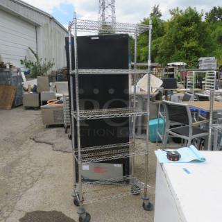 Metro shelving unit with 5 wire shelves, 30x14x80 inches, on casters for mobility. Appears in good condition outdoors.