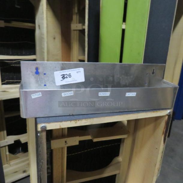 Stainless steel bottle rail, 22x4x6 inches, in good condition. Includes labels for various spirits. Lot number 326.