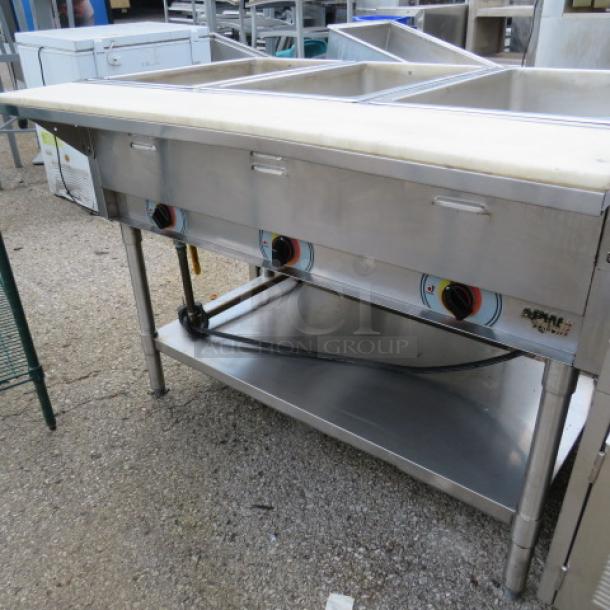 APW Wyott 3 well electric steam table with cutting board, stainless steel under shelf, on casters, 46x30x34, used.