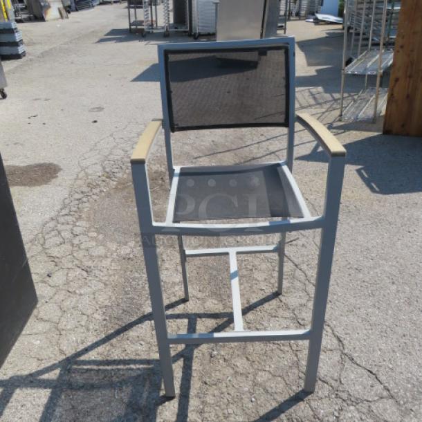 BFM bar height patio armchair in teak, aluminum, and mesh. Features sturdy frame, mesh back, and armrests. Good condition.