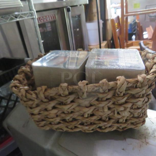 Woven basket containing packs of new bar drink coasters, wrapped in plastic, sitting on a table in a storage area.
