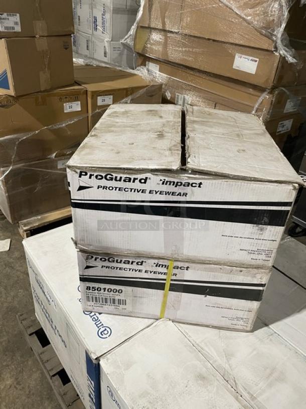 Box of 144 ProGuard by Impact 8501000 clear protective eyewear with black frames, brand new, displayed on a warehouse pallet.