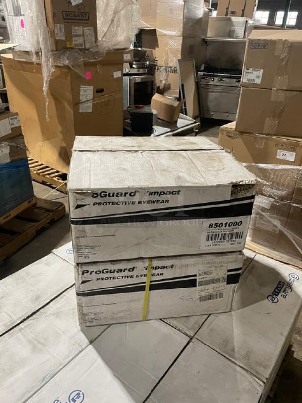 Box of ProGuard Model 8501000 clear protective eyewear with black frames. Brand new, 144 pairs per case.