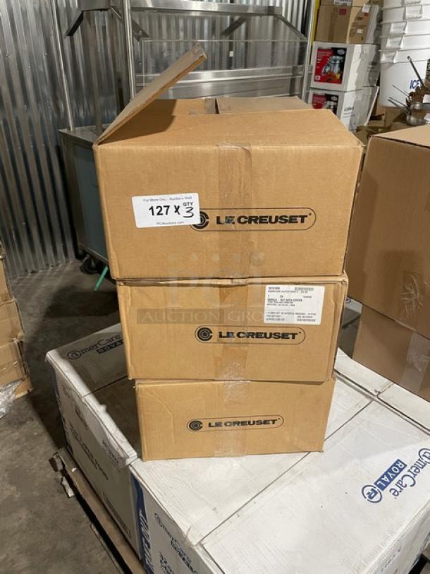 Three unopened boxes of Le Creuset enameled cast iron 6-3/4 qt. Signature Oval Dutch Ovens with lids, stacked in warehouse.