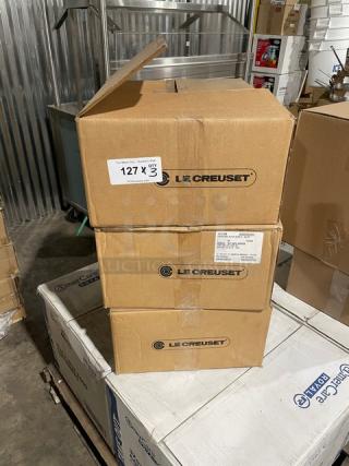 Three unopened boxes of Le Creuset enameled cast iron 6-3/4 qt. Signature Oval Dutch Ovens with lids, stacked in warehouse.